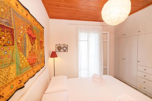 a white bedroom with a large painting on the wall at Porto Blue Horizon in Agios Ioannis