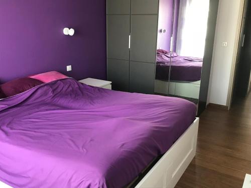 une chambre avec un lit violet et un miroir dans l'établissement 3 pièces près de la Promenade, à Nice