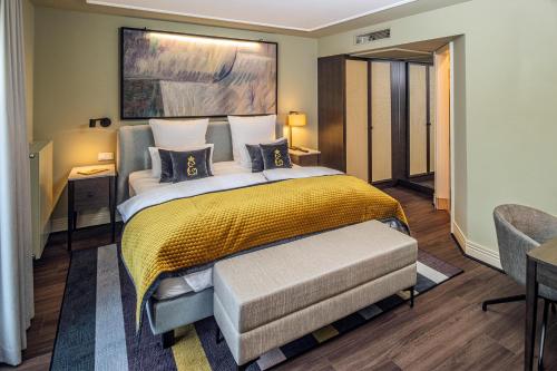 a bedroom with a large bed with a yellow blanket at Hotel Erbprinz - Gourmet & Spa in Ettlingen