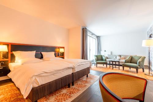 a large bedroom with a large bed and chairs at Hotel Erbprinz - Gourmet & Spa in Ettlingen