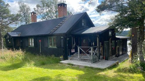 a black house with a porch in the grass at Messlingen 310 in Funäsdalen