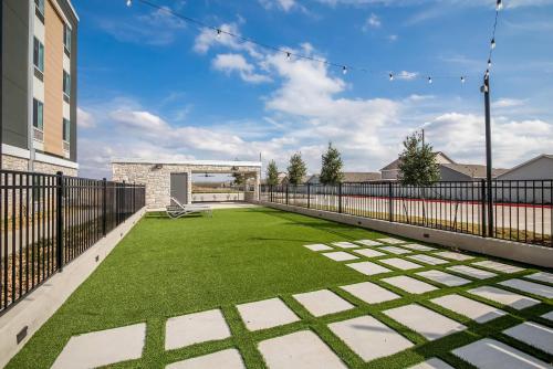 a large yard with green grass and a fence at Everhome Suites Bastrop in Bastrop