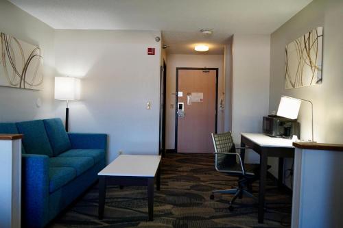 a hotel room with a couch and a table and a desk at Clarion Inn Fairborn - Dayton near Wright Patterson in Fairborn