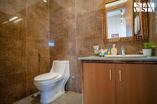 a bathroom with a toilet and a sink and a mirror at StayVista at Echoes of Ease with Bonfire & WiFi in Rishīkesh