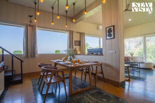 a dining room with a wooden table and chairs at StayVista at Echoes of Ease with Bonfire & WiFi in Rishīkesh
