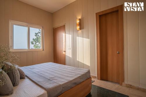 a bedroom with a bed and a window and a door at StayVista at Echoes of Ease with Bonfire & WiFi in Rishīkesh