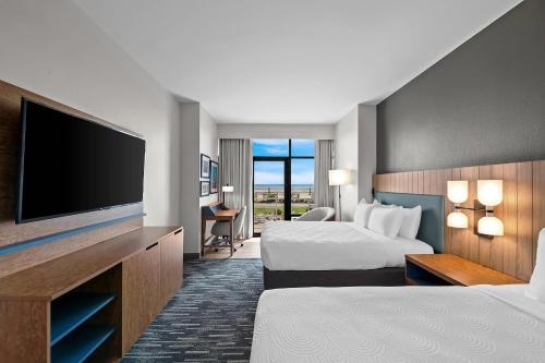 a hotel room with two beds and a flat screen tv at Country Inn & Suites by Radisson, Virginia Beach Oceanfront , VA in Virginia Beach