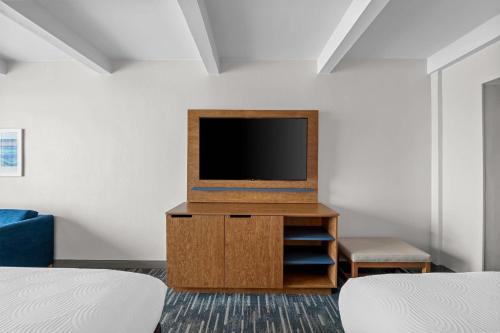 a living room with a tv on a cabinet at Country Inn & Suites by Radisson, Virginia Beach Oceanfront , VA in Virginia Beach