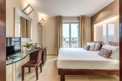 Una habitación de hotel con una cama, un escritorio y un televisor. en La Griffe Hotel Roma, en Roma