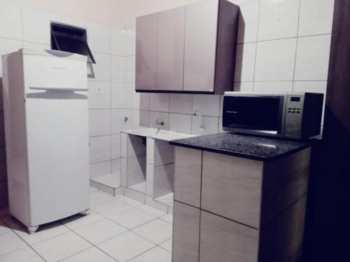 a kitchen with a microwave and a refrigerator at Casa in Fortaleza