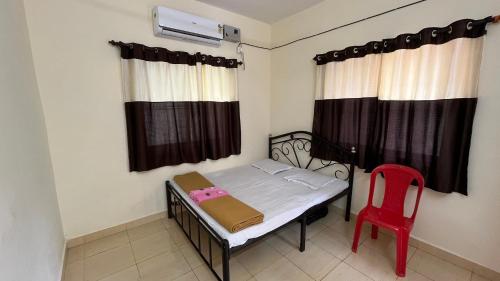 a small bedroom with a bed and a red chair at Ritu Holiday Home - Nagaon in Nagaon