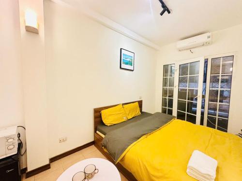 a bedroom with a yellow bed and a table at Home in Old Quarter HÀ NỘI - Ta Hien street in Hanoi