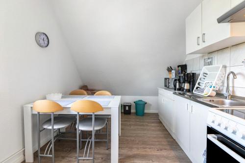 a kitchen with white cabinets and yellow stools at Neue ruhige Ferienwohnung in Klein Wittensee