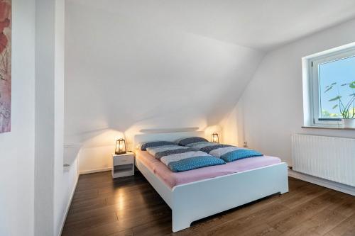 a white bedroom with a bed and a window at Neue ruhige Ferienwohnung in Klein Wittensee