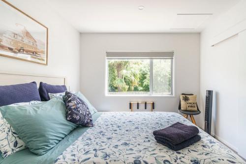 a bedroom with a bed with pillows and a window at Kombi Cottage Fully accessible in Tairua