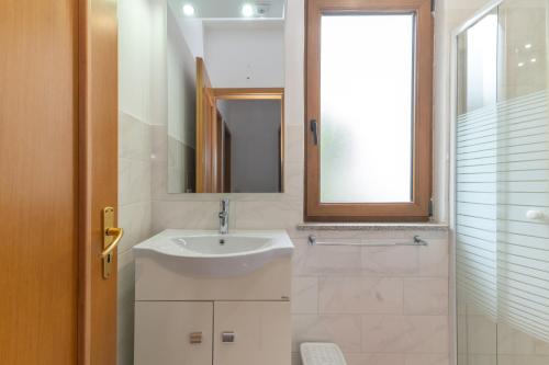 Guest House in the Center of Olbia في أولبيا: حمام أبيض مع حوض ومرآة