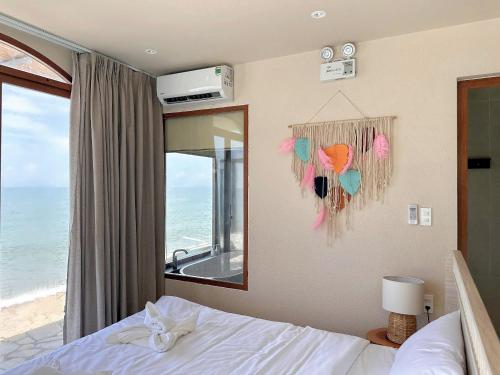 a bedroom with a bed and a mirror and the ocean at La Mer Bali Mui Ne in Phan Thiet