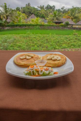 Ein Teller mit zwei Pizzen und Salat auf einem Tisch in der Unterkunft Villa Lumbung Sidemen in Sidemen