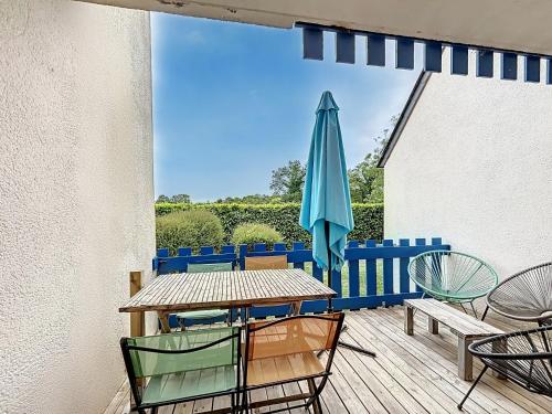 une terrasse avec une table et un parasol bleu dans l'établissement Appartement rez de jardin proche du centre ville de sarzeau, à Sarzeau