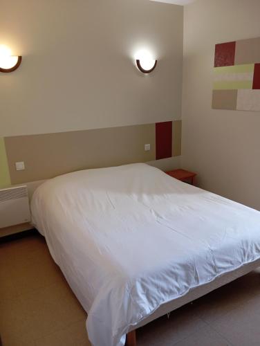 a bedroom with a white bed with two lights on it at Le relais du Perche in Les Croix Chemins