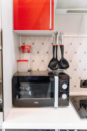 a black microwave on a kitchen counter with utensils at Двухкомнатные апартаменты на улице Естая, дом 89 напротив ТД Артур in Pavlodar