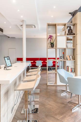 a room with chairs and a counter with a laptop at Grand Hôtel Clichy Paris in Clichy