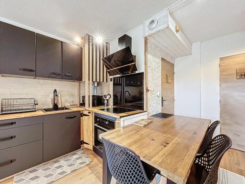una cucina con un tavolo di legno e alcune sedie di Appartement rez de jardin proche du centre ville de sarzeau a Sarzeau