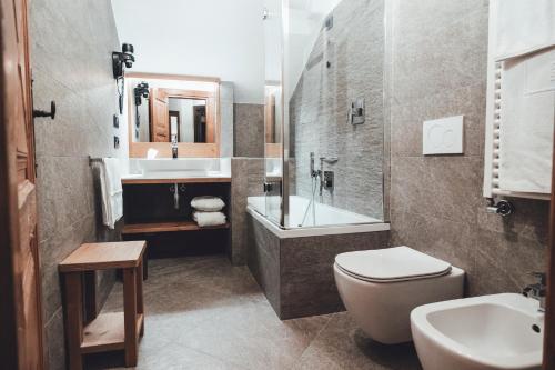 a bathroom with a toilet and a sink and a tub at Hotel Bouton d'Or - Courmayeur in Courmayeur