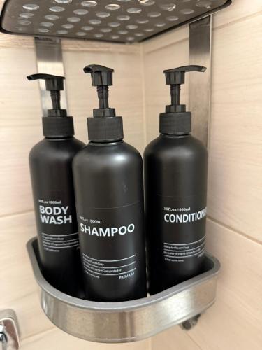 three black bottles in a metal container on a shelf at Boulevard Apartman in Nyíregyháza