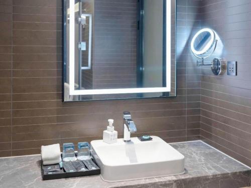 a bathroom with a white sink and a mirror at Xana Hotelle Zhuhai Gongbei Port in Zhuhai