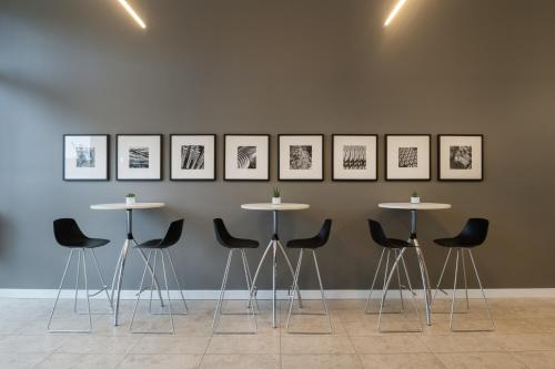 a group of tables and chairs against a wall with pictures at INNSiDE by Meliá Wolfsburg in Wolfsburg
