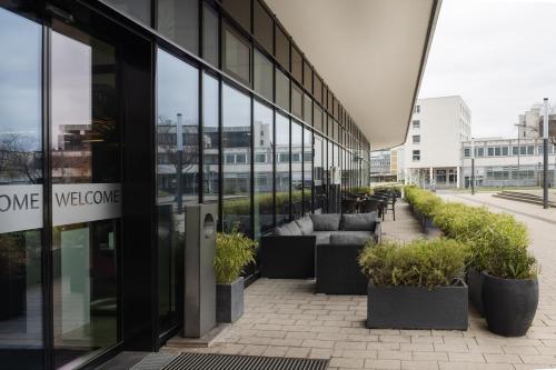 a glass building with couches and plants outside of it at INNSiDE by Meliá Wolfsburg in Wolfsburg