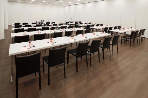 a conference room with white tables and black chairs at INNSiDE by Meliá Wolfsburg in Wolfsburg