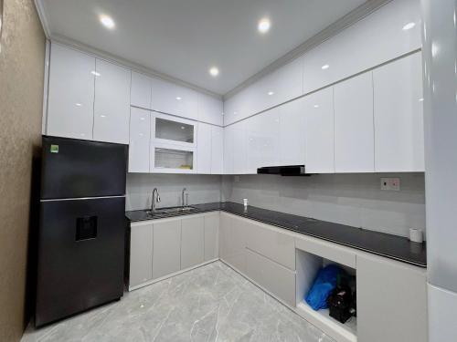 a kitchen with white cabinets and a black refrigerator at CAT BA Villas 5 Rooms in Cat Ba