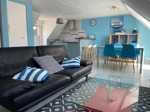 a living room with a black leather couch and blue walls at Le Bleu, T2 proche plage de Morgat in Crozon