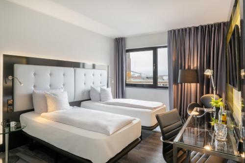 a hotel room with two beds and a glass table at INNSiDE by Meliá Wolfsburg in Wolfsburg