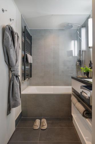 a bathroom with a tub and a pair of slippers at INNSiDE by Meliá Wolfsburg in Wolfsburg
