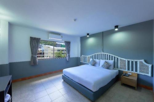 a bedroom with a white bed and a window at Nora Bukit Hotel in Ban Sam Kong
