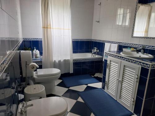 a blue and white bathroom with a toilet and a sink at House pc in Porto da Cruz