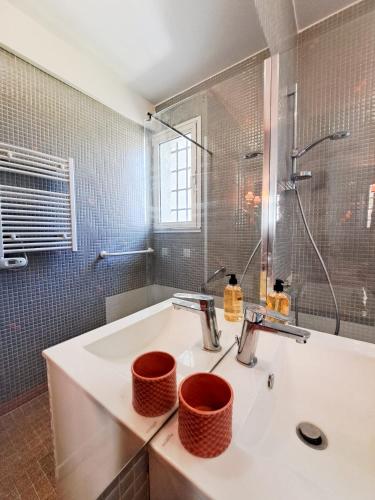 une salle de bain blanche avec un lavabo et une douche dans l'établissement Nonni - MAISON FAMILIALE AVEC JARDIN, PROCHE DE LA GARE ET A 10MIN DE LA PLAGE, à Royan