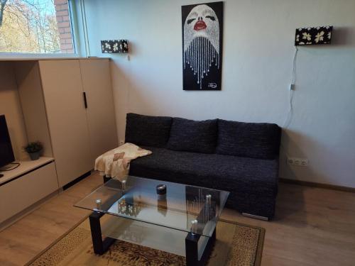 a living room with a couch and a glass table at Jaunystės studija in Klaipėda