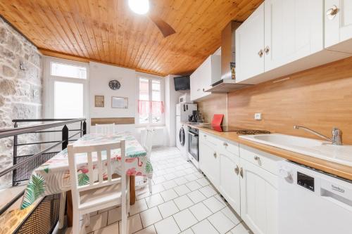 une cuisine avec des armoires blanches et un plafond en bois dans l'établissement Les Petits Loups - Proche Station de Ski, à Le Mont-Dore