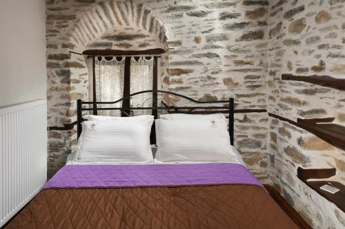 a bed in a room with a stone wall at Archontiko Michael since 1868 in Vizitsa