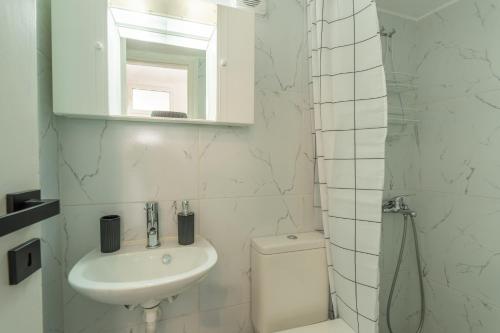 a white bathroom with a sink and a toilet at Chrysi Guesthouse in Rethymno