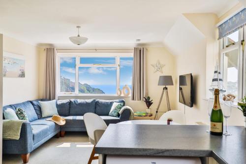 un salon avec un canapé bleu et une table dans l'établissement Beer View Cottage, à Beer