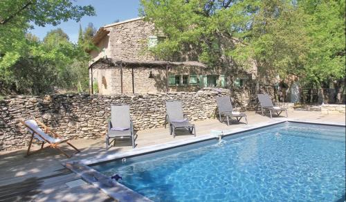 une piscine avec des chaises et un mur en pierre dans l'établissement Authentique Bergerie Coeur Luberon, à Lacoste