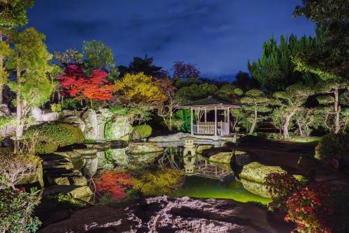 a painting of a garden with a pond and a gazebo at kumihimo kobe in Wada