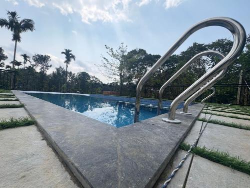 a swimming pool with a metal stairway leading into a pool at The Golden Oak A Classic Villas in Vythiri
