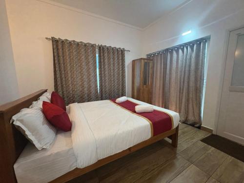 a bedroom with a bed with red pillows at The Golden Oak A Classic Villas in Vythiri