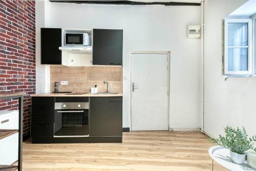 une cuisine avec des appareils noirs et un mur en briques dans l'établissement L'Atelier d'Angers, à Angers
